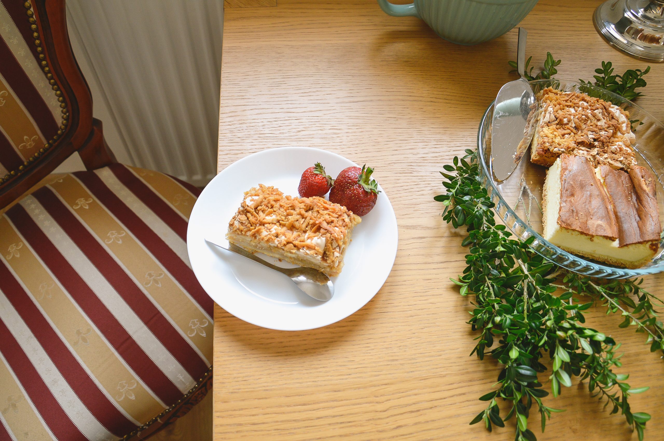 Jabłecznik na talerzu z truskawkami oraz sernik, ustawiony na drewnianym stole obok antycznego krzesła, agroturystyka, noclegi w górach