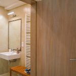 Nowoczesna beżowa łazienka w apartamencie, z umywalką, dużym lustrem oprawionym kryształkami i masywnymi drewnianymi drzwiami wewnętrznymi, klasyczny apartament, agroturystyka, noclegi w górach