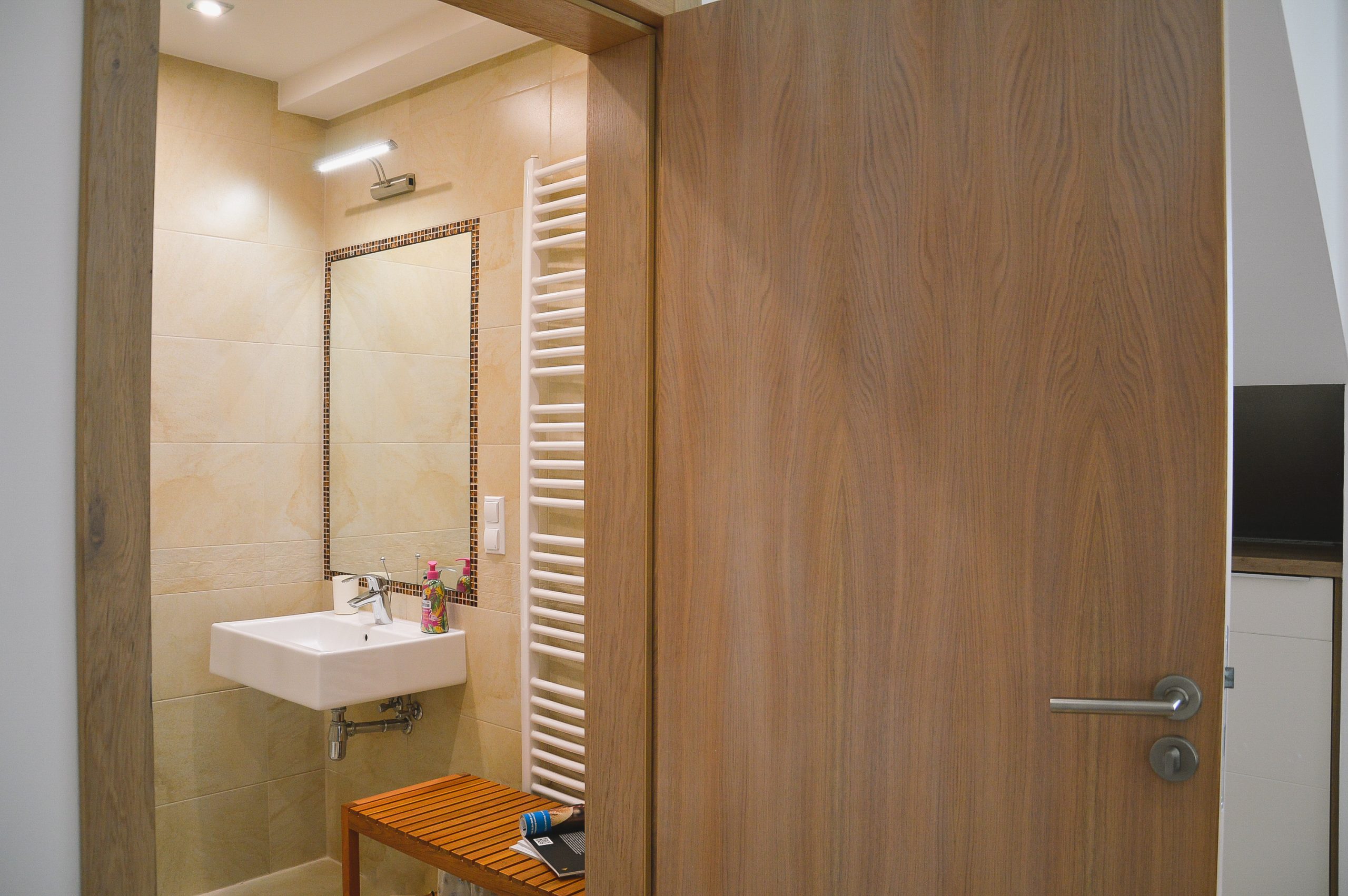 Nowoczesna beżowa łazienka w apartamencie, z umywalką, dużym lustrem oprawionym kryształkami i masywnymi drewnianymi drzwiami wewnętrznymi, klasyczny apartament, agroturystyka, noclegi w górach