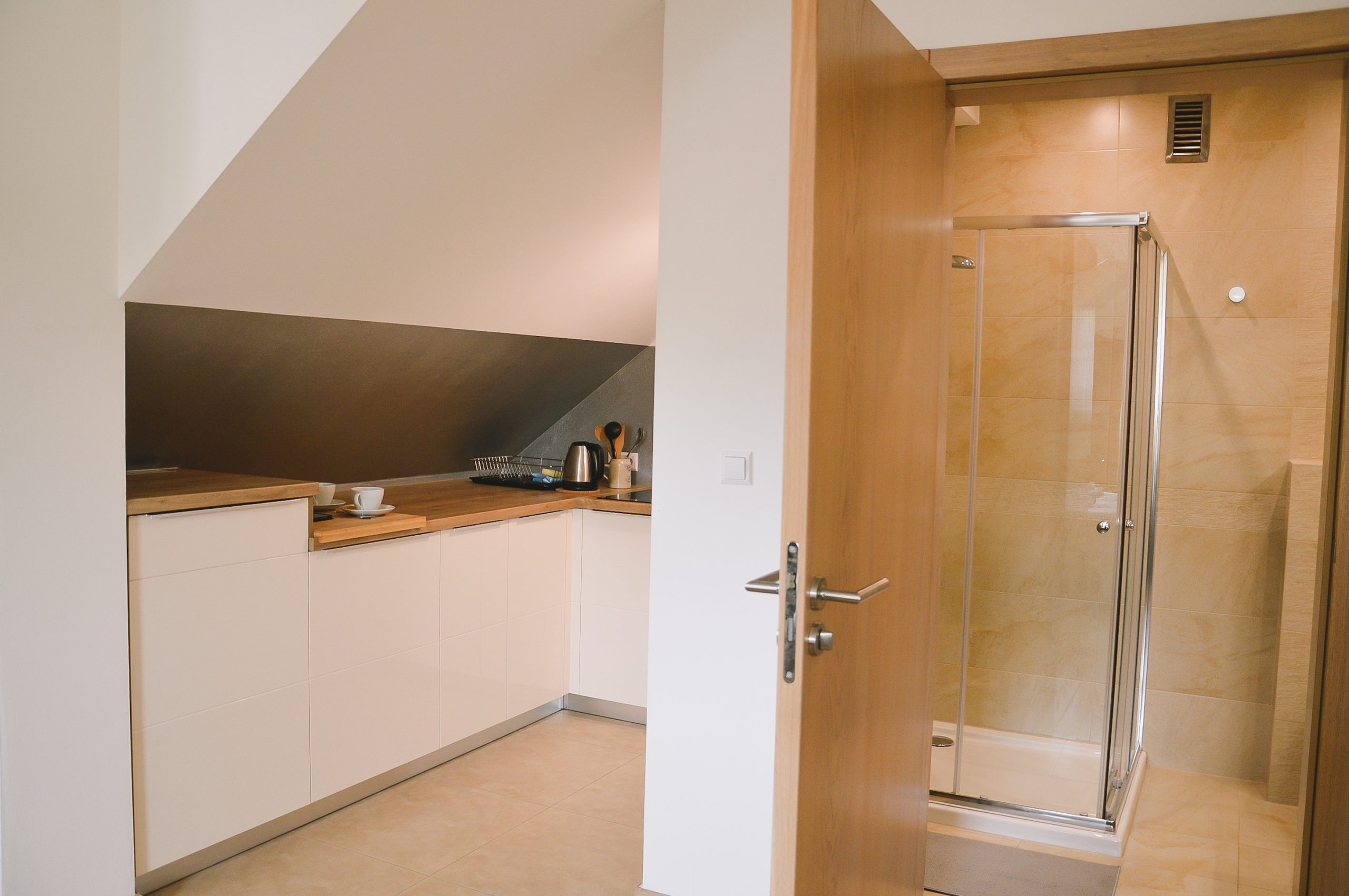 Nowoczesna biała kuchnia w górach z drewnianym blatem oraz beżowa łazienka, agroturystyka, hotele i noclegi w górach