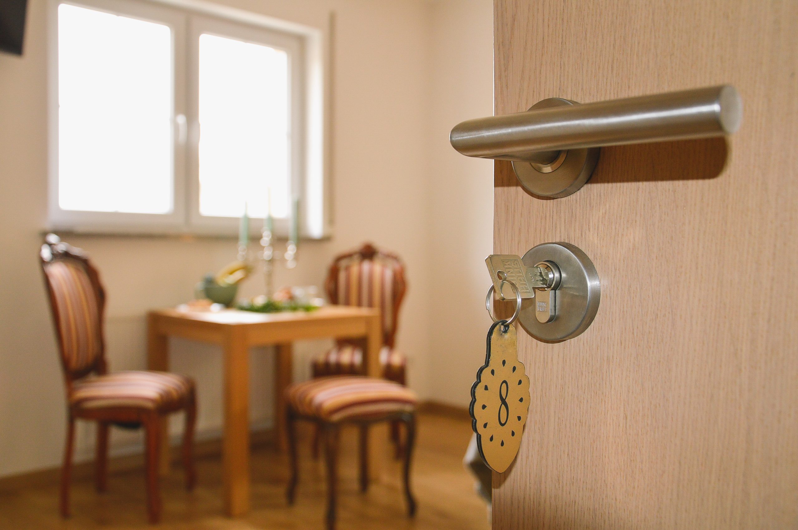 Wejście do apartamentu agroturystycznego z ręcznie malowaną grafiką wokół drzwi, widoczna stylowa jadalnia i klucz z góralskim brelokiem, klasyczny apartament, blisko Term Gorce