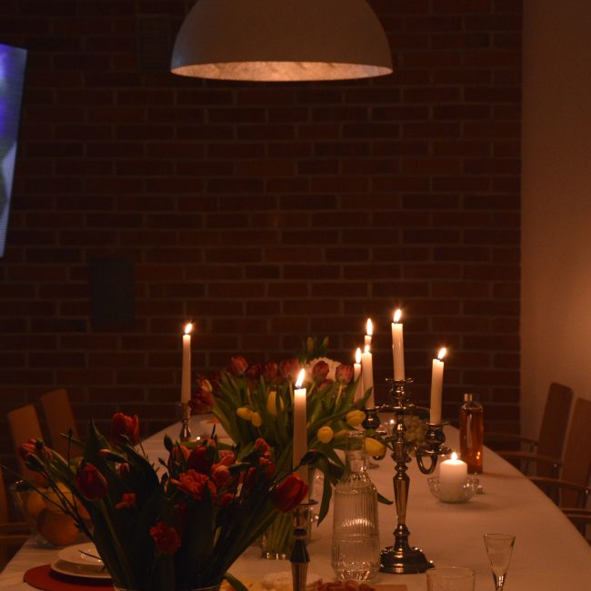 Sala biesiadna z elegancko udekorowanym stołem, świece, kwiaty i naczynia, przytulne oświetlenie