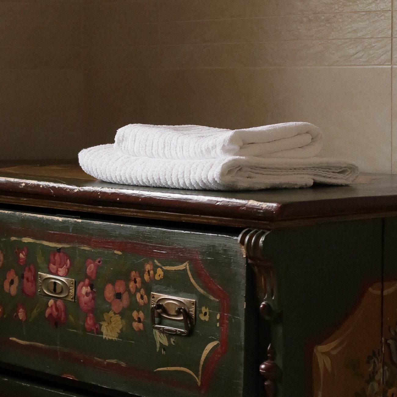 Tradycyjna malowana szafka z białymi ręcznikami w górskim apartamencie, noclegi w Gorcach, agroturystyka.